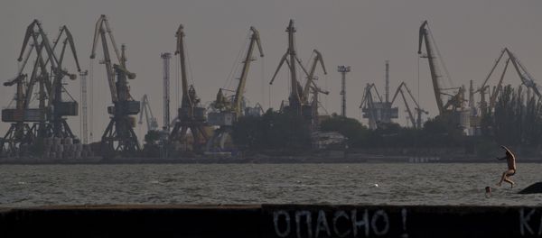 A man jumps in the Sea of Azov, backdropped by cranes of the commercial port, at dusk in Mariupol, Ukraine, Sunday, May 18, 2014 A man jumps in the Sea of Azov, backdropped by cranes of the commercial port, at dusk in Mariupol, Ukraine, Sunday, May 18, 2014 - Sputnik International