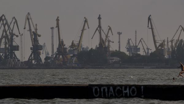 A man jumps in the Sea of Azov, backdropped by cranes of the commercial port, at dusk in Mariupol, Ukraine, Sunday, May 18, 2014 - Sputnik International