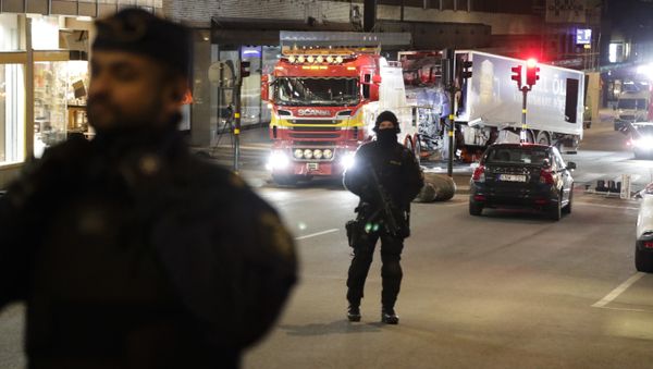 Police officers guard the scene as a truck is pulled away by a service car after it was driven into a department store in Stockholm, Sweden, Saturday, April 8, 2017 - Sputnik International