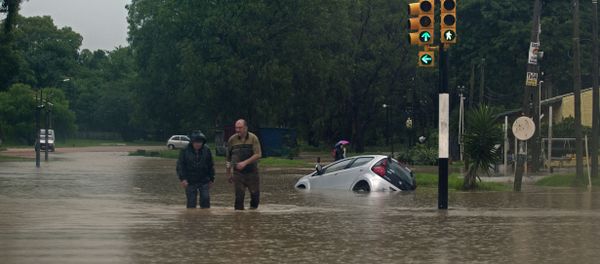 Two men wade through a flooded street in the locality of Solymar, Ciudad de la Costa, Canelones, some 20 km east of Montevideo, during floods caused by heavy rains hitting the country, on February 7, 2014 Two men wade through a flooded street in the locality of Solymar, Ciudad de la Costa, Canelones, some 20 km east of Montevideo, during floods caused by heavy rains hitting the country, on February 7, 2014 - Sputnik International