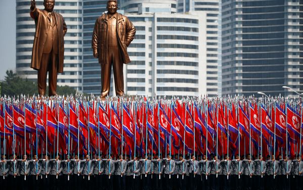 People carry flags in front of statues of North Korea founder Kim Il Sung (L) and late leader Kim Jong Il during a military parade marking the 105th birth anniversary Kim Il Sung, in Pyongyang April 15, 2017. - Sputnik International