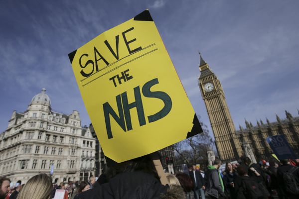 A protester holds a placard in support of the NHS in front of the Elizabeth Tower, also known as Big Ben at the Houses of Parliament during a march against private companies' involvement in the National Health Service (NHS) and social care services provision and against cuts to NHS funding in central London on March 4, 2017 - Sputnik International