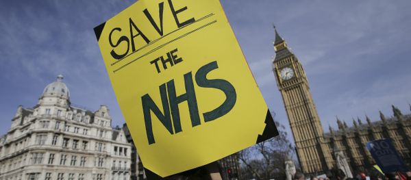A protester holds a placard in support of the NHS in front of the Elizabeth Tower, also known as Big Ben at the Houses of Parliament during a march against private companies' involvement in the National Health Service (NHS) and social care services provision and against cuts to NHS funding in central London on March 4, 2017 A protester holds a placard in support of the NHS in front of the Elizabeth Tower, also known as Big Ben at the Houses of Parliament during a march against private companies' involvement in the National Health Service (NHS) and social care services provision and against cuts to NHS funding in central London on March 4, 2017 - Sputnik International