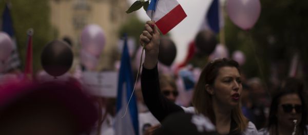 A woman holds a rose and a French flag during a demonstration in what was described as a march of support for all French security forces, in Paris A woman holds a rose and a French flag during a demonstration in what was described as a march of support for all French security forces, in Paris - Sputnik International
