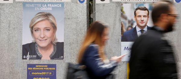 People walk past campaign posters of Marine Le Pen (L), French National Front (FN) political party leader, and Emmanuel Macron (R), head of the political movement En Marche! (Onwards!), two of the eleven candidates who run in the 2017 French presidential election in Paris, France, April 10, 2017 - Sputnik International