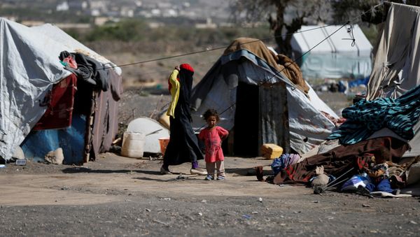 A woman walks past a child at a camp for people displaced by the war, near Sanaa, Yemen April 25, 2017 - Sputnik International