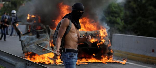 A demonstrator stands near fire during a rally against Venezuela's President Nicolas Maduro in Caracas, Venezuela April 24, 2017 - Sputnik International
