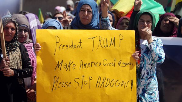 Kurdish women carry flags and a banner as they protest, in the northeastern city of Qamishli, against Turkish airstrikes on the headquarters of the Kurdish fighters from the People's Protection Units (YPG) in Mount Karachok on Tuesday, Syria April 26, 2017 - Sputnik International