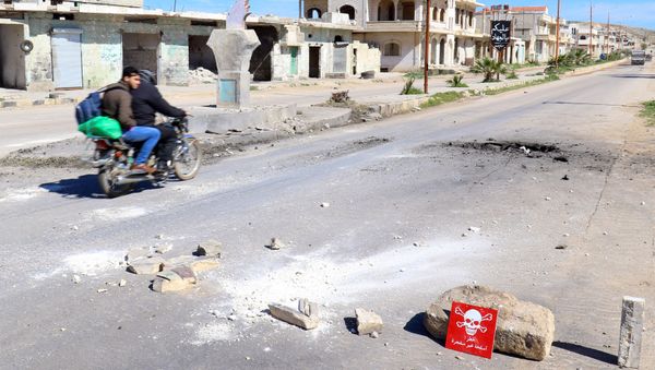 Men ride a motorbike past a hazard sign at a site hit by an airstrike on Tuesday in the town of Khan Sheikhoun in rebel-held Idlib, Syria April 5, 2017 Men ride a motorbike past a hazard sign at a site hit by an airstrike on Tuesday in the town of Khan Sheikhoun in rebel-held Idlib, Syria April 5, 2017 - Sputnik International