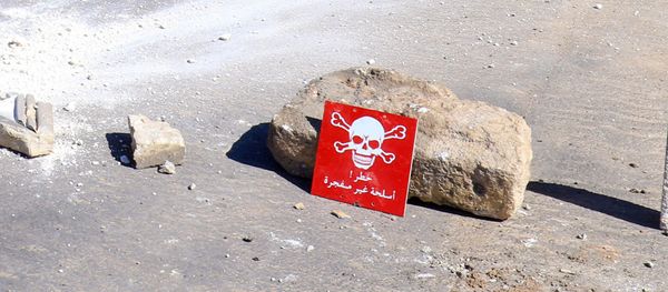 Men ride a motorbike past a hazard sign at a site hit by an airstrike on Tuesday in the town of Khan Sheikhoun in rebel-held Idlib, Syria April 5, 2017 - Sputnik International