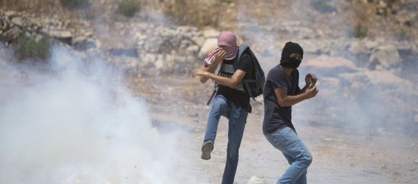 Palestinian protesters react to a tear gas canister fired by Israeli troops during a protest with solidarity hunger strike of Palestinian prisoners in the Israeli jails Palestinian protesters react to a tear gas canister fired by Israeli troops during a protest with solidarity hunger strike of Palestinian prisoners in the Israeli jails - Sputnik International