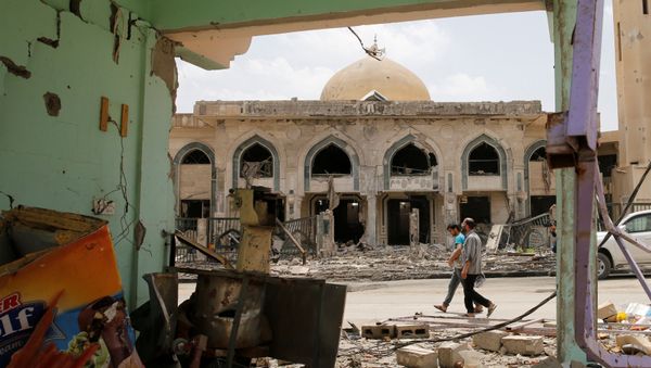 Iraqi men walk past a damaged building after the end of the battles between the Iraqi forces and Islamic State militants at their district in western Mosul, Iraq, April 30, 2017 - Sputnik International