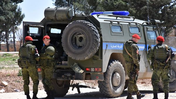 Members of the Russian Military police stand guard in the northern city of Manbij as Syrians who fled the city of Aleppo due to the fighting prepare to return to their hometown, on April 5, 2017 - Sputnik International