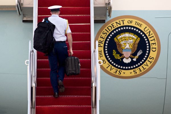 A Military aide carries 'the football', the leather briefcase stocked with the classified nuclear war plan, in his right hand as he walks up the stairs of Air Force One at Andrews Air Force Base, in Md. - Sputnik International