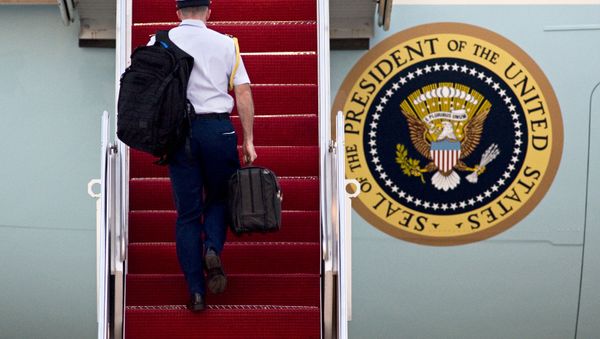 A Military aide carries 'the football', the leather briefcase stocked with the classified nuclear war plan, in his right hand as he walks up the stairs of Air Force One at Andrews Air Force Base, in Md. - Sputnik International