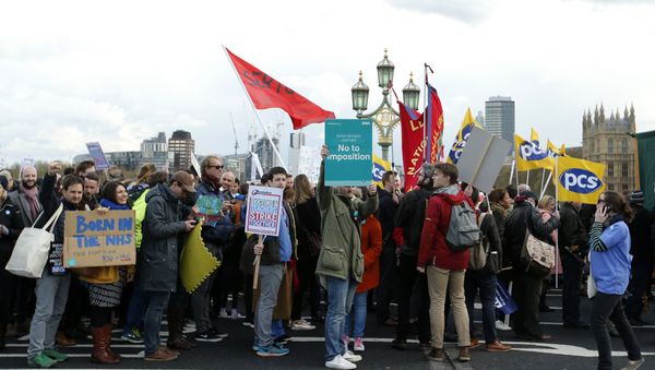 Protestors holding banners walk across Westminster Bridge towards the Palace of Westminster as they demonstrate in support of junior doctors who are staging a 48 hour all out strike, in London, Tuesday, April 26, 2016 - Sputnik International