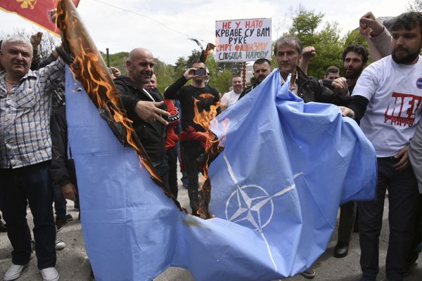 Anti-NATO demonstrators burn a NATO flag in front of a a banner that reads: No to NATO, your hands are bloody - Death to fascism, freedom to the people, during a protest outside the hall before the parliament session in Cetinje, Montenegro, Friday, April 28, 2017 - Sputnik International