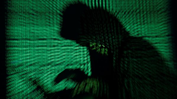 A hooded man holds a laptop computer as cyber code is projected on him in this illustration picture taken on May 13, 2017 - Sputnik International