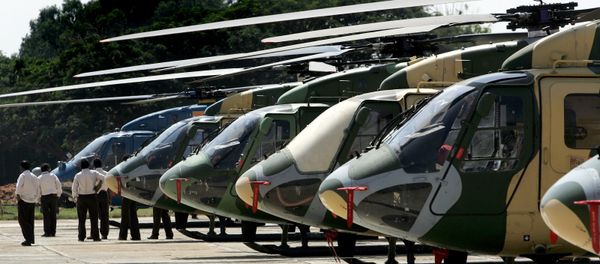 Officials walk past a line of parked Dhruv helicopters of India's Hindustan Aeronautics Ltd. (HAL) standing on the tarmac at The HAL helicopter division in Bangalore Officials walk past a line of parked Dhruv helicopters of India's Hindustan Aeronautics Ltd. (HAL) standing on the tarmac at The HAL helicopter division in Bangalore - Sputnik International