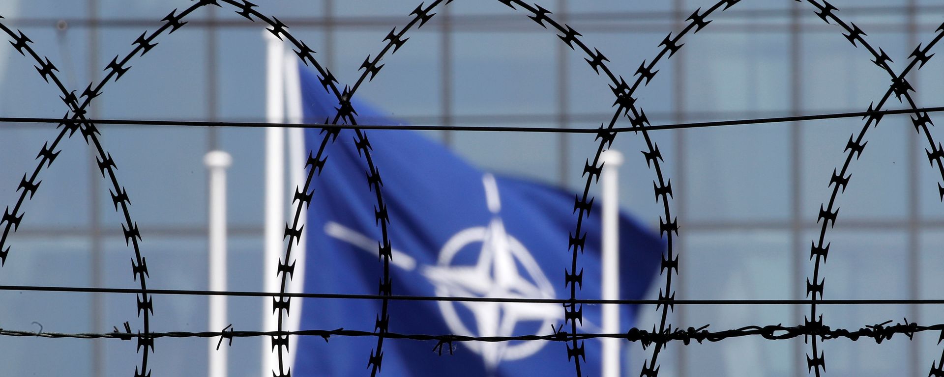 The NATO flag is seen through barbed wire as it flies in front of the new NATO Headquarters in Brussels, Belgium May 24, 2017 The NATO flag is seen through barbed wire as it flies in front of the new NATO Headquarters in Brussels, Belgium May 24, 2017 - Sputnik International, 1920, 12.01.2022