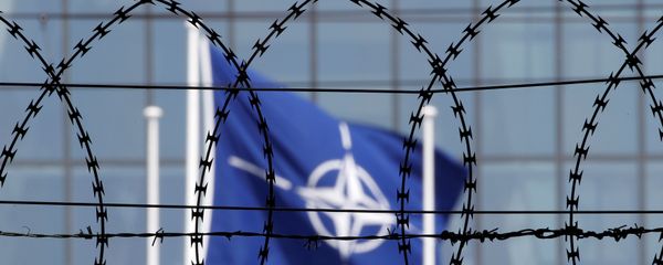 The NATO flag is seen through barbed wire as it flies in front of the new NATO Headquarters in Brussels, Belgium May 24, 2017 - Sputnik International