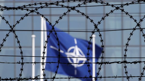 The NATO flag is seen through barbed wire as it flies in front of the new NATO Headquarters in Brussels, Belgium May 24, 2017 - Sputnik International