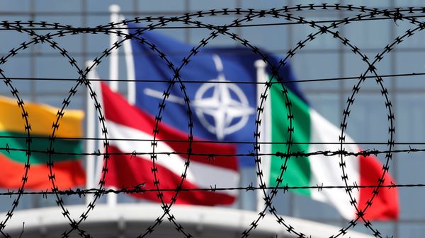 The NATO flag is seen through barbed wire as it flies in front of the new NATO Headquarters in Brussels, Belgium May 24, 2017 - Sputnik International