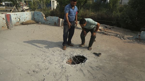 Indian civilians inspect the rooftop of a house damaged by mortar shells allegedly fired from the Pakistan side of the border, at a residential area near the Line of Control at the India Pakistan border at Jhanghar village, in Nowshera, India, Sunday, May 14,2017 - Sputnik International