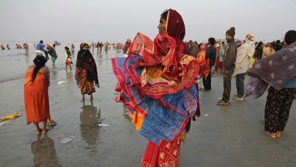 A woman holds saris of companions taking holy dips at the confluence of the Bay of Bengal and Ganges River on Makar Sankranti festival in Gangasagar, India, Saturday, Jan. 14, 2017 A woman holds saris of companions taking holy dips at the confluence of the Bay of Bengal and Ganges River on Makar Sankranti festival in Gangasagar, India, Saturday, Jan. 14, 2017 - Sputnik International