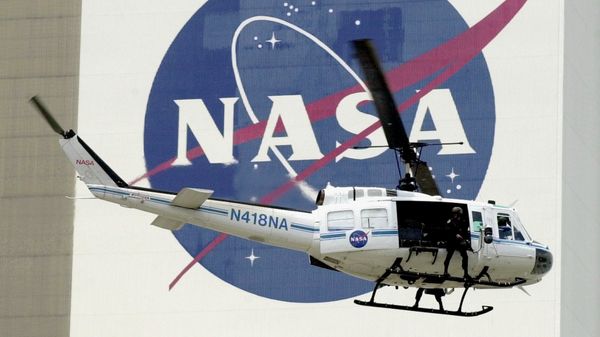 A NASA security helicopter flies by the NASA logo on the Vehicle Assembly Building - Sputnik International