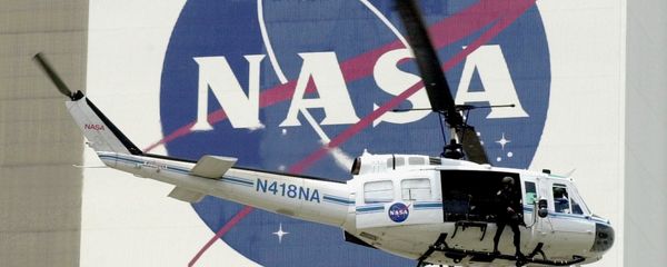 A NASA security helicopter flies by the NASA logo on the Vehicle Assembly Building - Sputnik International