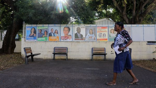 A woman walks past campaign posters as she arrives to a polling station in La Possession on the French Indian Ocean island of La Reunion during the first round of the French legislative elections on June 11, 2017 A woman walks past campaign posters as she arrives to a polling station in La Possession on the French Indian Ocean island of La Reunion during the first round of the French legislative elections on June 11, 2017 - Sputnik International