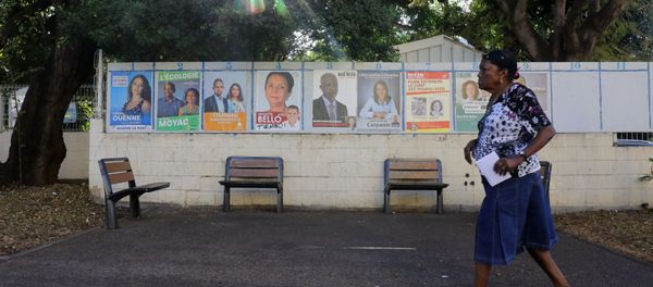 A woman walks past campaign posters as she arrives to a polling station in La Possession on the French Indian Ocean island of La Reunion during the first round of the French legislative elections on June 11, 2017 - Sputnik International