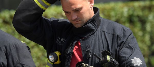 Firefighters rest near a tower block, severely damaged in a serious fire, in north Kensington, West London, Britain June 14, 2017. - Sputnik International
