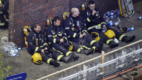 Firefighters rest as they take a break in battling a massive fire that raged in a high-rise apartment building in London, Wednesday, June 14, 2017. - Sputnik International