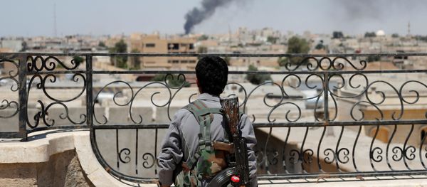 A Kurdish fighter from the People's Protection Units (YPG) looks at a smoke after an coalition airstrike in Raqqa, Syria June 16, 2017 - Sputnik International