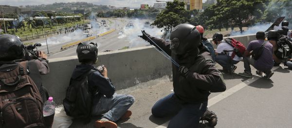 An anti-government demonstrator aims a slingshot during clashes with security forces along a highway in Caracas, Venezuela, Monday, June 19, 2017 - Sputnik International