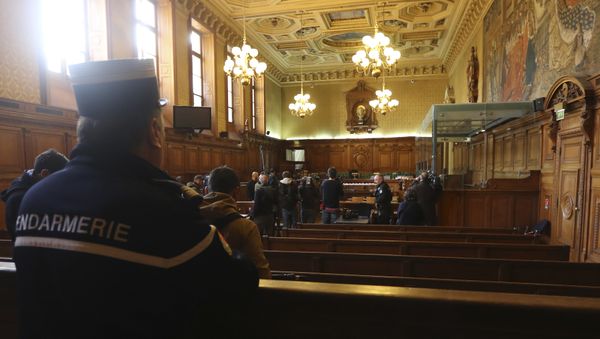 A gendarme looks on (L) as reporters work next to a bulletproof dock in the courtroom of a Special Court of Assizes at the Paris courthouse, prior to the start of the trial of a jihadist cell known as the Cannes-Torcy cell, long considered one of the most dangerous in France, on April 20, 2017 - Sputnik International