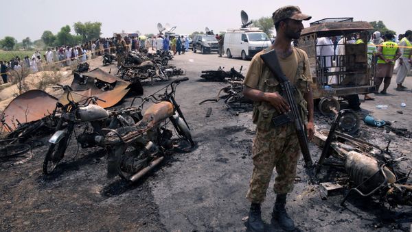 A soldier stands guard amid burnt out cars and motorcycles at the scene of an oil tanker explosion in Bahawalpur, Pakistan - Sputnik International