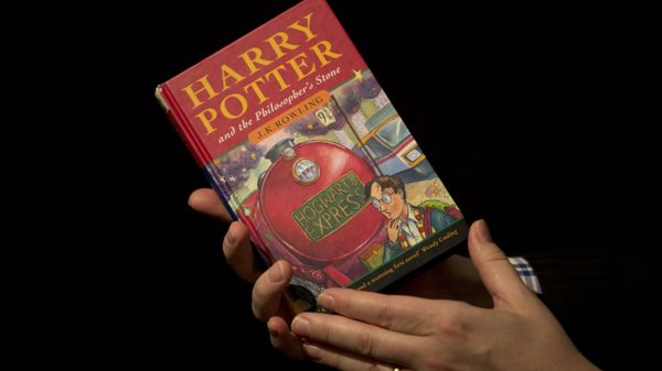 Sotheby's Director of the Department of Printed Books and Manuscripts Dr Philip Errington poses for photographers with a first edition copy of the first Harry Potter book Harry Potter and the Philosopher's Stone. - Sputnik International