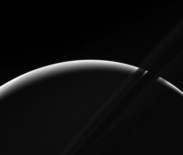 NASA's Cassini spacecraft peers toward a sliver of Saturn's sunlit atmosphere while the icy rings stretch across the foreground as a dark band - Sputnik International