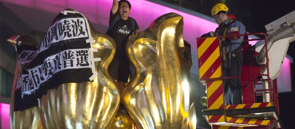 A police officer and a fireman try to remove a pro-democracy activist who shouts slogan and hangs a cloth that reads Release Liu Xiaobo unconditionally, Hong Kong people want genuine universal suffrage, on a giant flower statue bequeathed by Beijing in 1997 in Golden Bauhinia Square of Hong Kong Wednesday, June 28, 2017. - Sputnik International