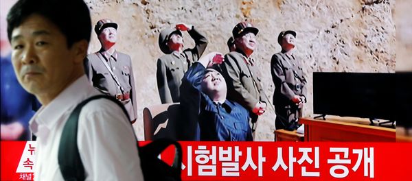 A man walks past a TV broadcasting still photographs released by North Korea's state-run television KRT of North Korea's Hwasong-14 missile, a new intercontinental ballistic missile, which they said was successfully tested, at a railway station in Seoul, South Korea, July 4, 2017. - Sputnik International