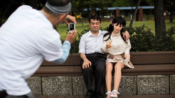 In this picture taken on May 9, 2017, a man takes pictures of physiotherapist Masayuki Ozaki and his silicone sex doll Mayu in Tokyo Bay. - Sputnik International