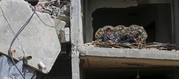 Mohammed Keferna, 14, sits on a couch in his family's building that was damaged by Israeli strikes during last summer's Israel-Hamas war, in Beit Hanoun, northern Gaza Strip, Friday, Jan. 30, 2015 - Sputnik International