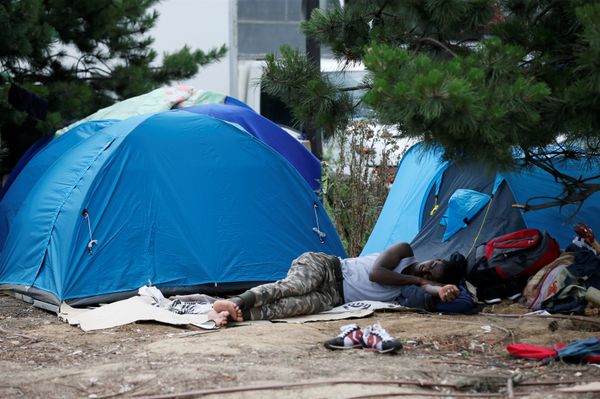 A migrant sleeps next to tents installed in a street near the entrance of the reception center for migrants and refugees at porte de La Chapelle, north of Paris, France, July 6, 2017 - Sputnik International
