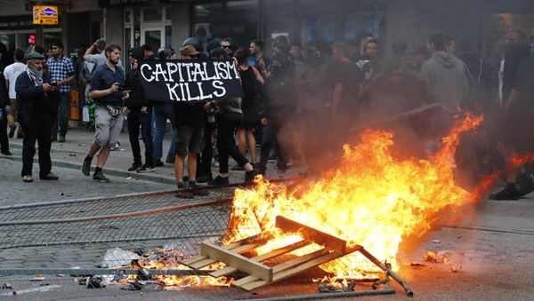 A protester holds a banner next to the bonfire during a demonstration at the G20 summit in Hamburg, Germany, July 7, 2017 - Sputnik International