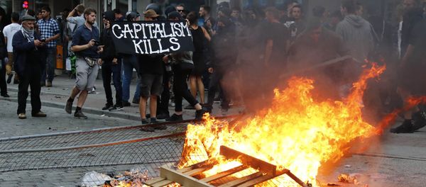 A protester holds a banner next to the bonfire during a demonstration at the G20 summit in Hamburg, Germany, July 7, 2017 A protester holds a banner next to the bonfire during a demonstration at the G20 summit in Hamburg, Germany, July 7, 2017 - Sputnik International