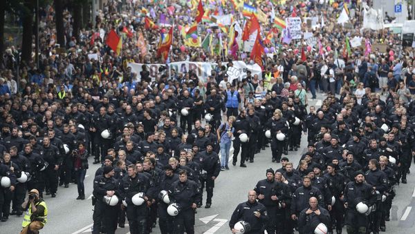 German riot police officers walk in front of protesters during demonstrations at the G20 summit in Hamburg, Germany, July 8, 2017 German riot police officers walk in front of protesters during demonstrations at the G20 summit in Hamburg, Germany, July 8, 2017 - Sputnik International