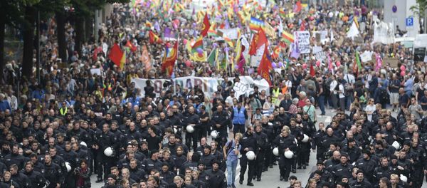 German riot police officers walk in front of protesters during demonstrations at the G20 summit in Hamburg, Germany, July 8, 2017 German riot police officers walk in front of protesters during demonstrations at the G20 summit in Hamburg, Germany, July 8, 2017 - Sputnik International